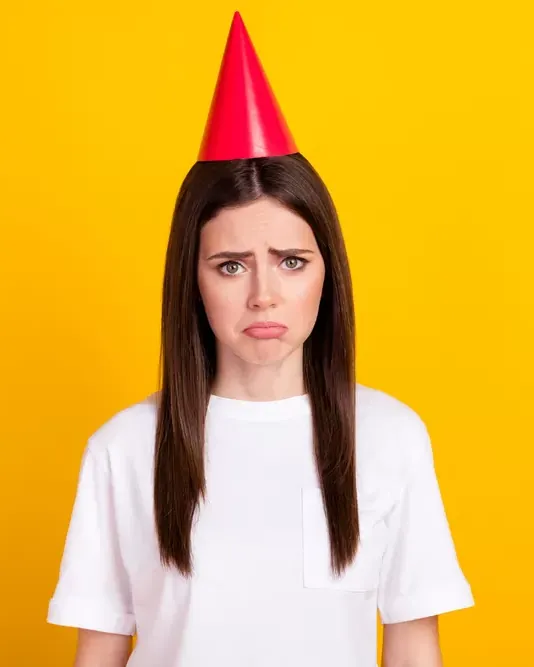 Invitada con gorro de fiesta y cara de frustración