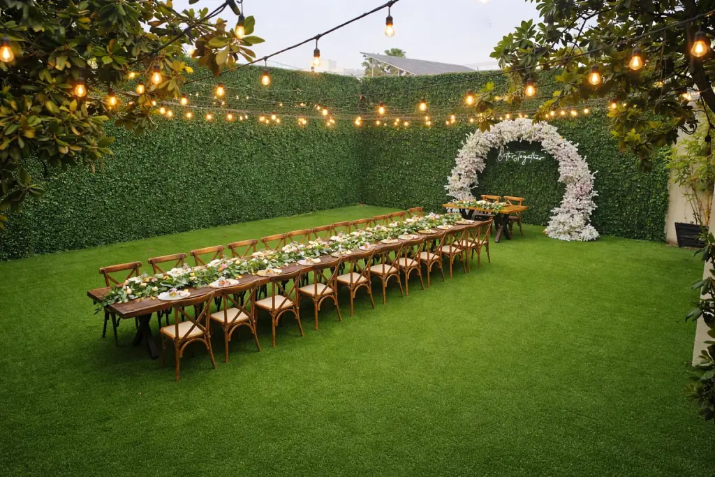 Jardín con luces colgantes y una mesa larga montada para un evento